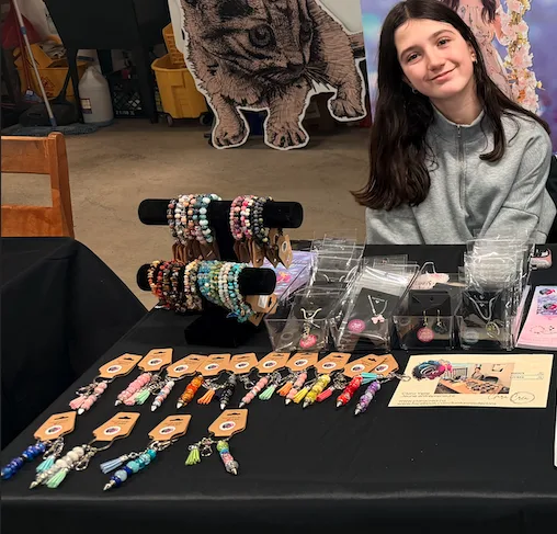 Clara derrière son kiosque de bracelets, colliers et porte-clés
